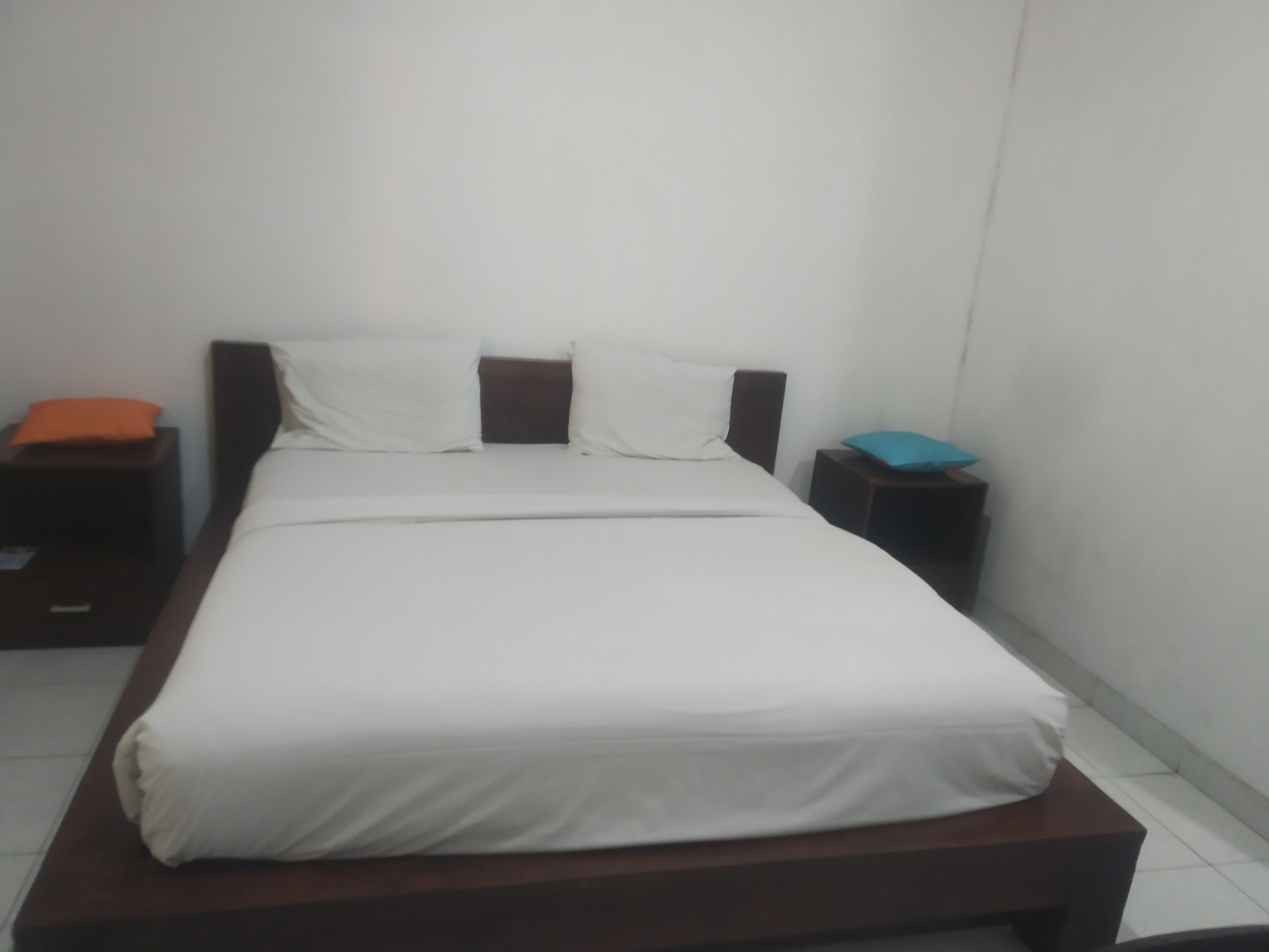 Una habitación estándar de hotel con una cama individual, una mesita de noche y una pequeña mesa.