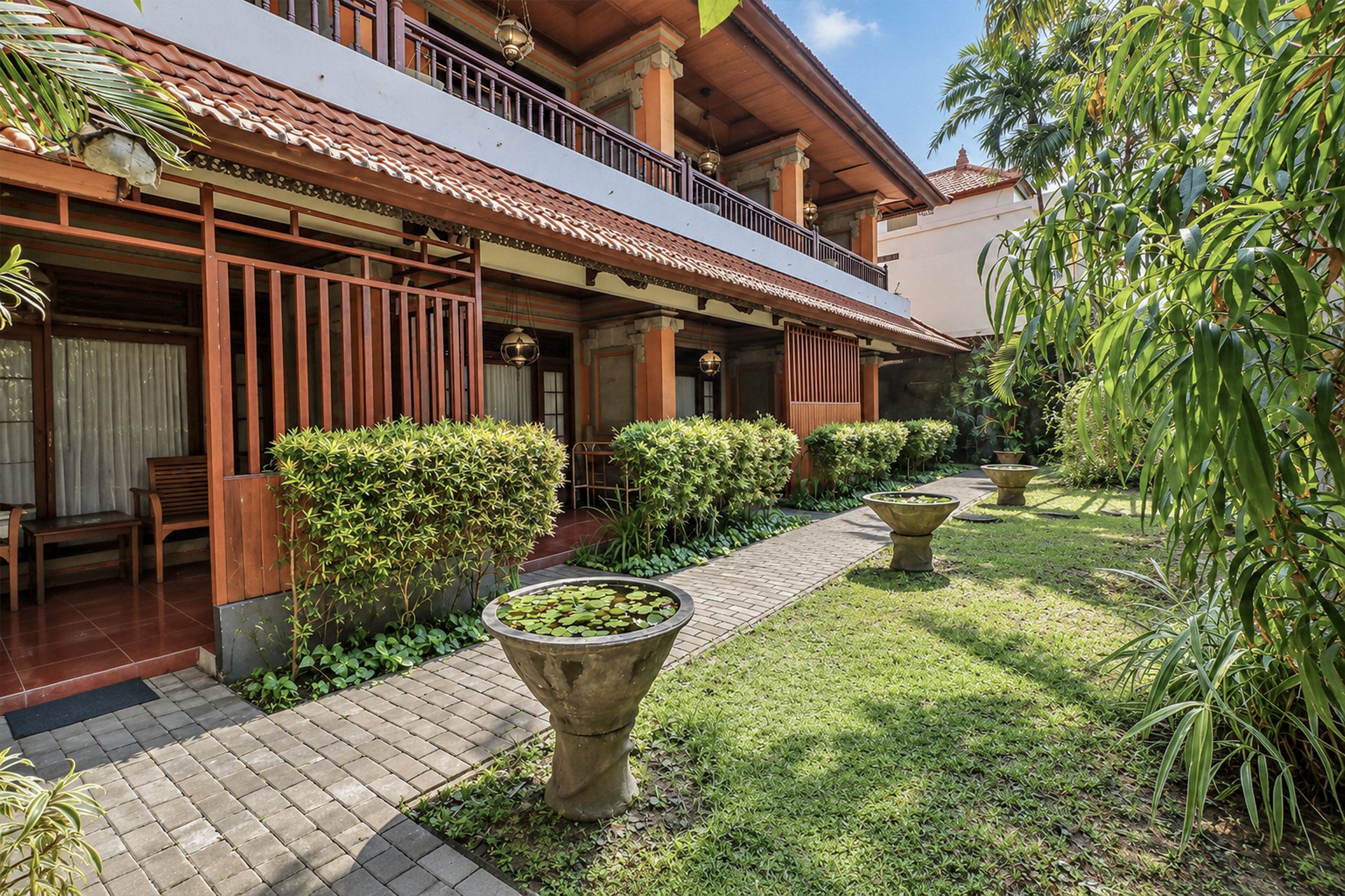 A traditional building with a covered walkway, potted plants, and a clear sky.