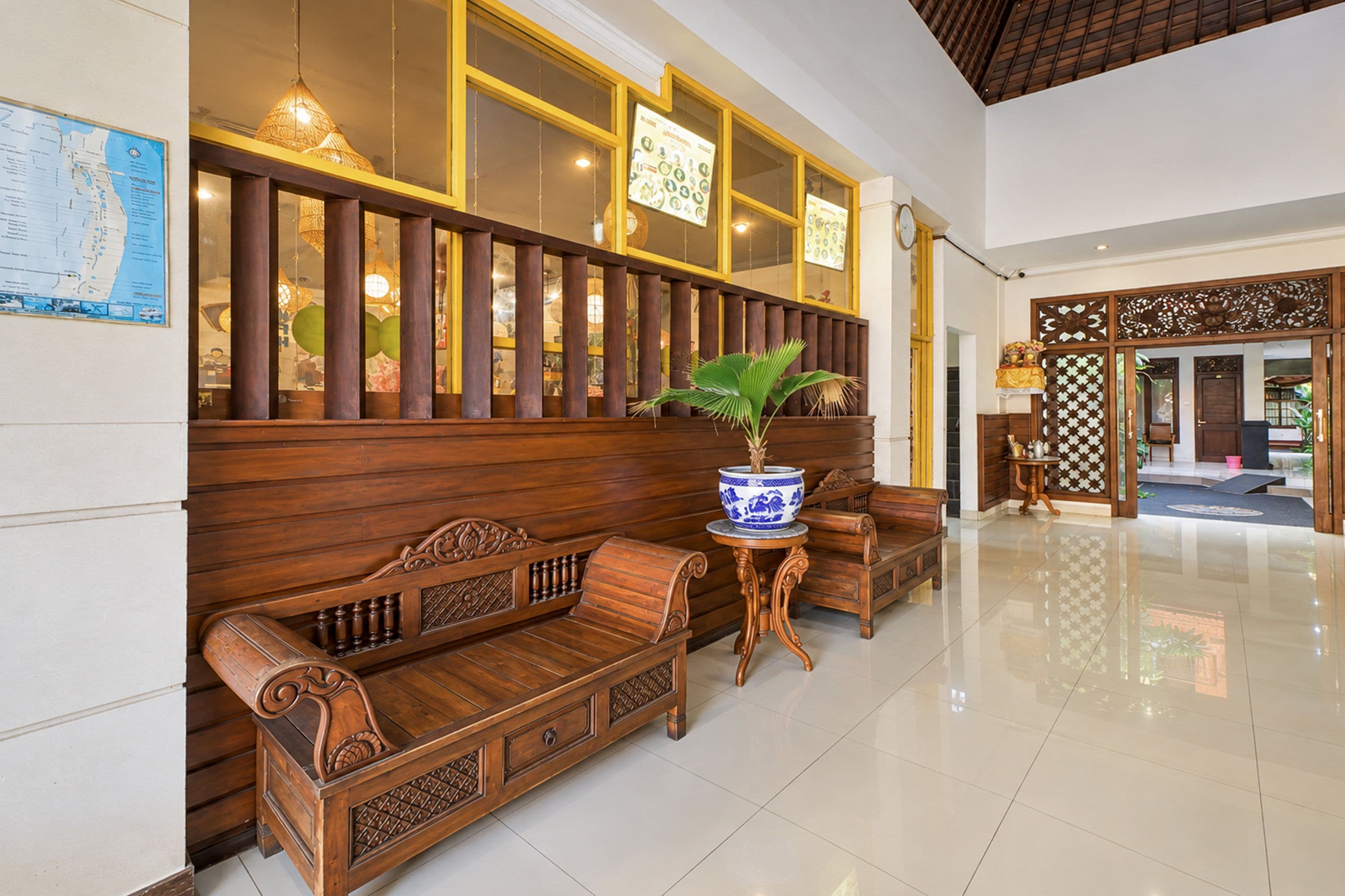 A traditional wooden bench with intricate carvings, a potted plant, and a wall-mounted map.