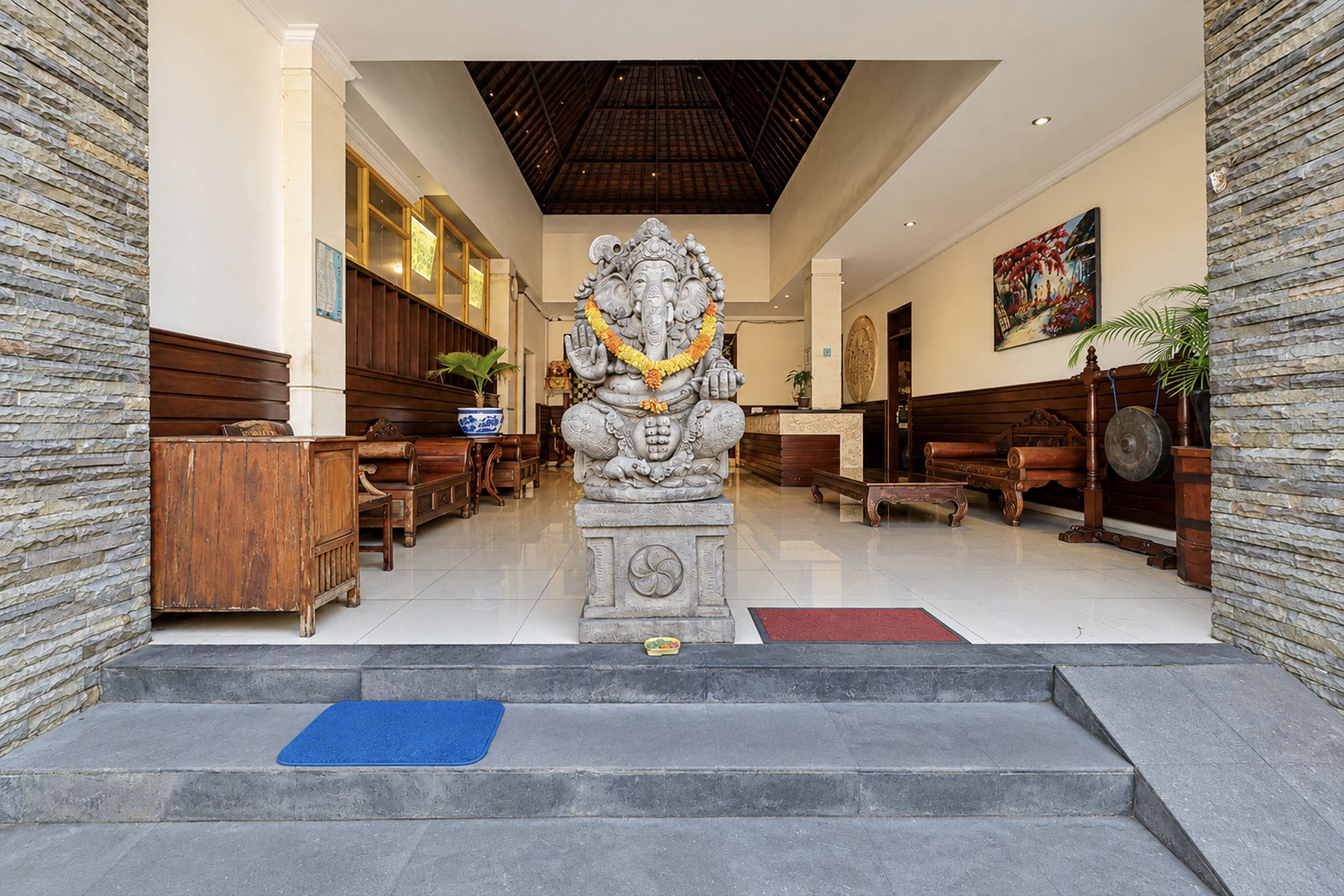 A reception area with a statue, wooden benches, and a tiled floor.
