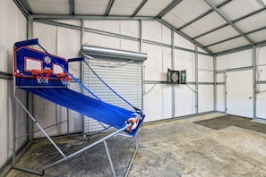 A sports hall with a blue netted basketball hoop, a dartboard, and a metal frame structure. - Lake & Leisure-Dock, Game Room, Golf Cart, (Winchester)