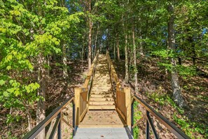 A wooden boardwalk leading through a forest with trees on both sides. - Lake & Leisure-Dock, Game Room, Golf Cart, (Winchester)