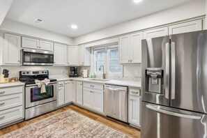 A modern kitchen with stainless steel appliances, white cabinetry, and a marble countertop. - Lake & Leisure-Dock, Game Room, Golf Cart, (Winchester)
