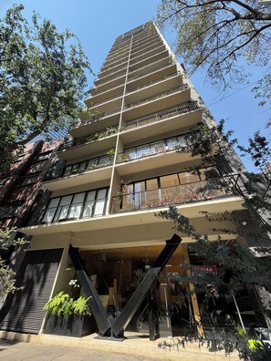 A multi-story building with balconies, large windows, and outdoor plants. - Comfortable apartment undergoing renovation in downtown Mexico City (Ciudad de México)