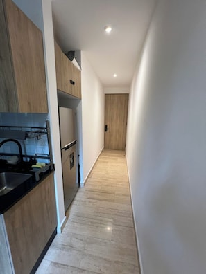 A narrow hallway with a kitchen area on one side, featuring cabinets, a sink, and a countertop. - Comfortable apartment undergoing renovation in downtown Mexico City (Ciudad de México)