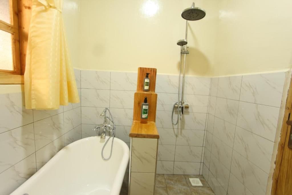 Ein Badezimmer mit einer Badewanne, einer Dusche und einem Holzboden mit einer Flasche.