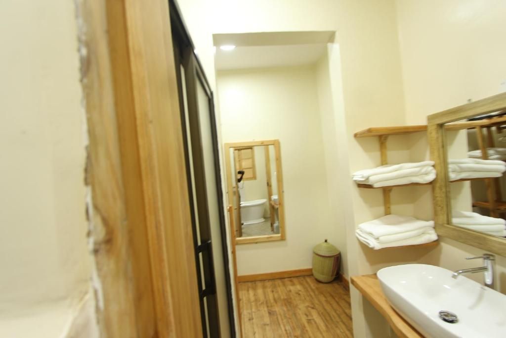 A bathroom with a wooden floor, a sink with a mirror above it, and a towel rack with folded towels.