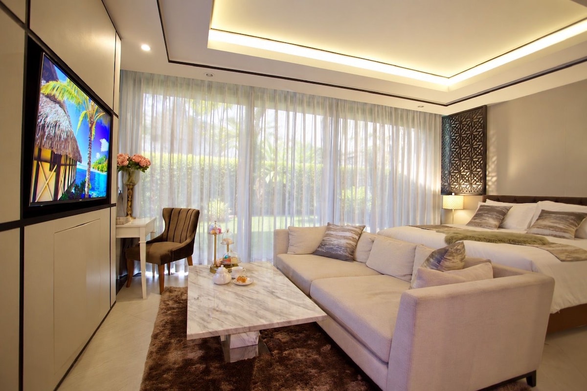 Una sala moderna con un sofá, un sillón, una mesa de centro y un televisor montado en la pared.