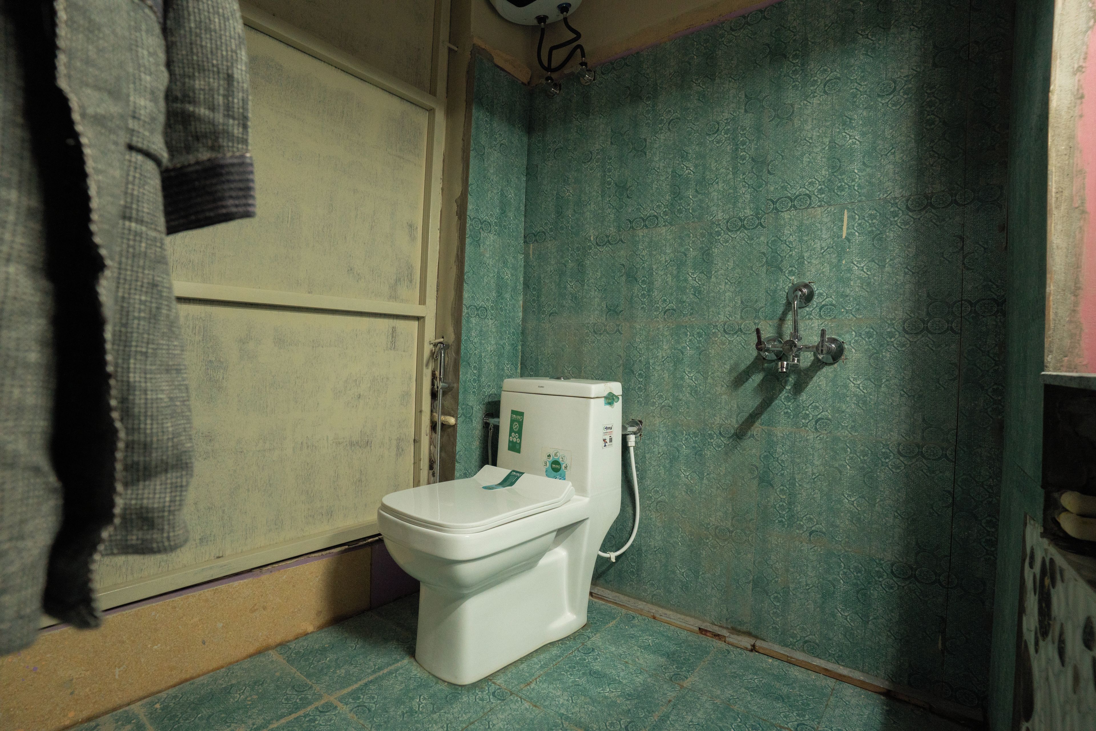 A small bathroom with a toilet, a shower, and a door.