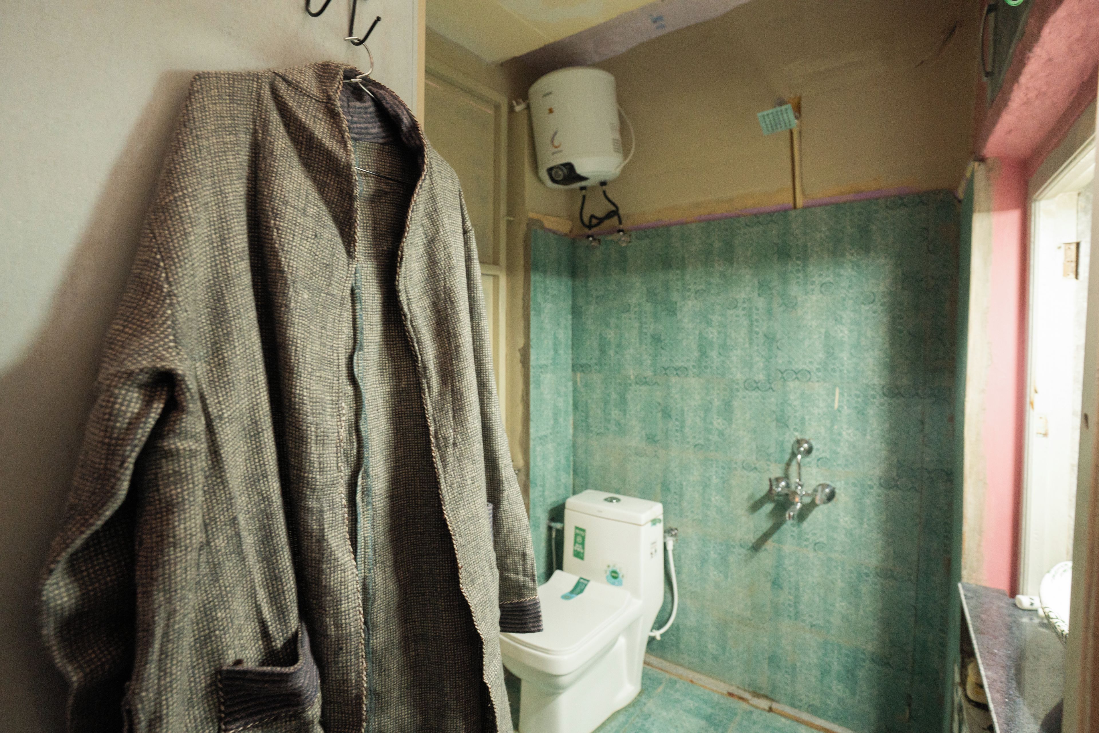 Un baño con inodoro, ducha y toalla colgada en la pared.