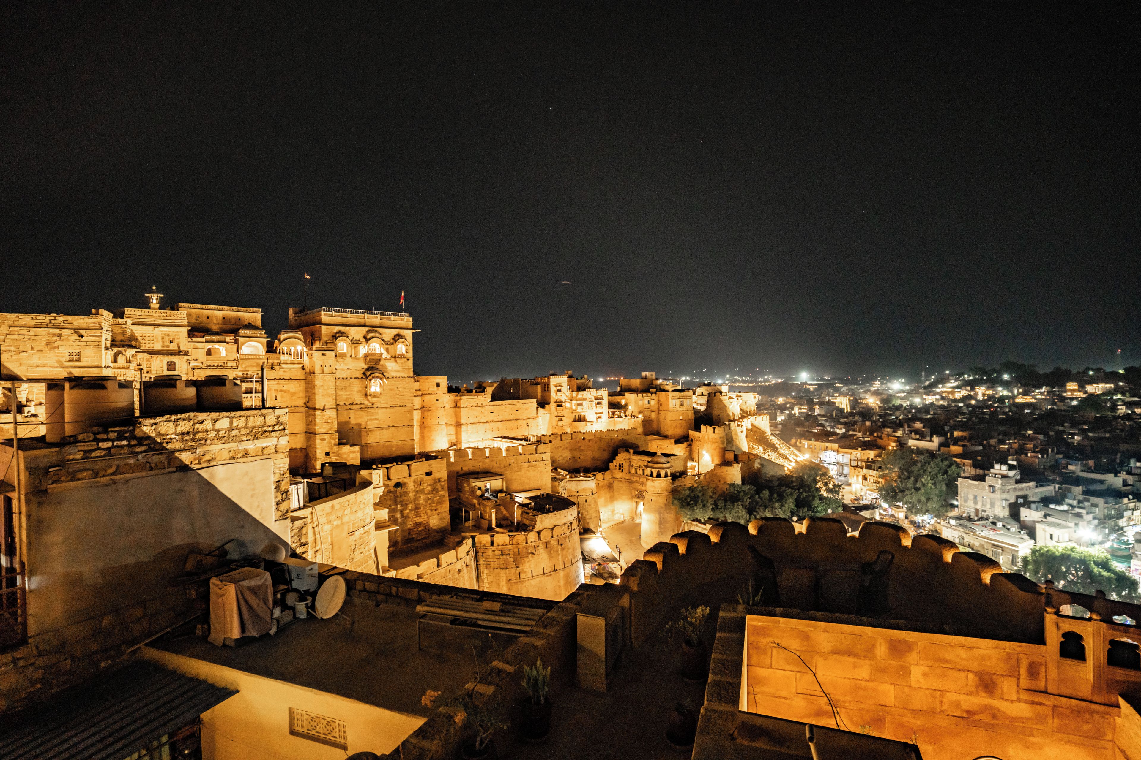 A historic fort with multiple levels and a view of the city at night.