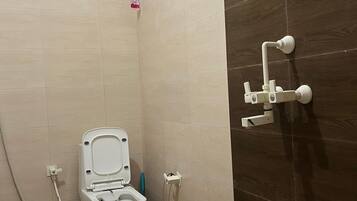 Un baño con inodoro, secamanos y un cubo.