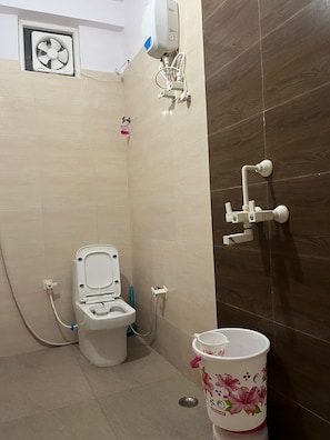 Ein Badezimmer mit Toilette, Handtrockner und einem Eimer.