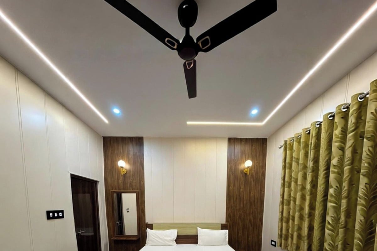 Ein Schlafzimmer mit einem Bett, einem Deckenventilator, Einbaustrahlern, Holzverkleidung und einem Fenster mit Vorhängen.