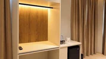A modern room with a built-in desk, a small black trash bin, and a curtain-covered window.