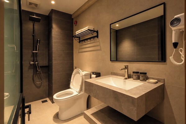 A modern bathroom with a shower, toilet, sink, and a hairdryer mounted on the wall. - Aurora Suite (Miri)