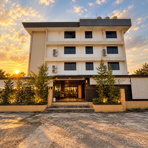Ein mehrstöckiges Hotel mit schlichter Fassade, großen Fenstern und Klimaanlagen.