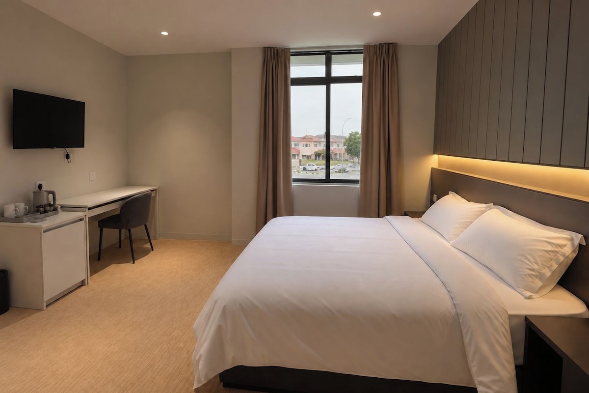 Habitació d'hotel amb un llit, escriptori, cadira, televisió i finestra amb cortines.