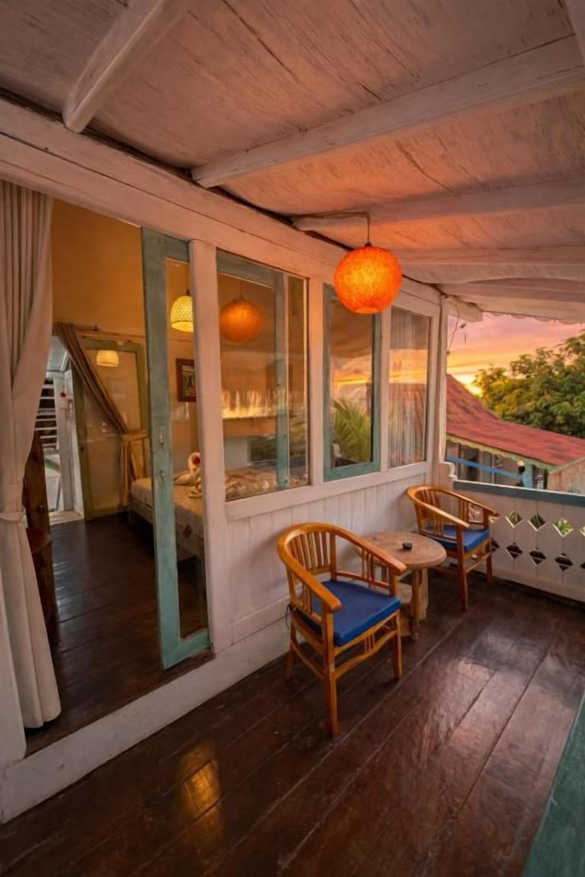 Une terrasse en bois avec deux chaises et une table, donnant sur un jardin.