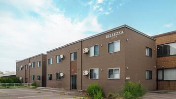 A multi-story building with the name 'BELLEZZA' on the facade, featuring a brick exterior, multiple windows, and air conditioning units.