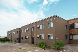 A multi-story building with the name 'BELLEZZA' on the facade, featuring a brick exterior, multiple windows, and air conditioning units. - Bellezza 101 (Asahikawa)