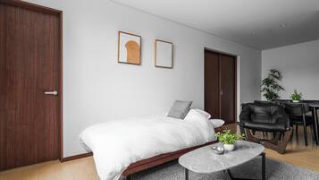 A modern bedroom with a bed, a small table, and a desk area.