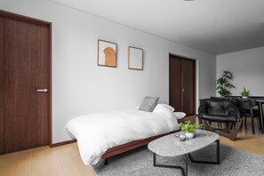A modern bedroom with a bed, a small table, and a desk area. - Bellezza 101 (Asahikawa)