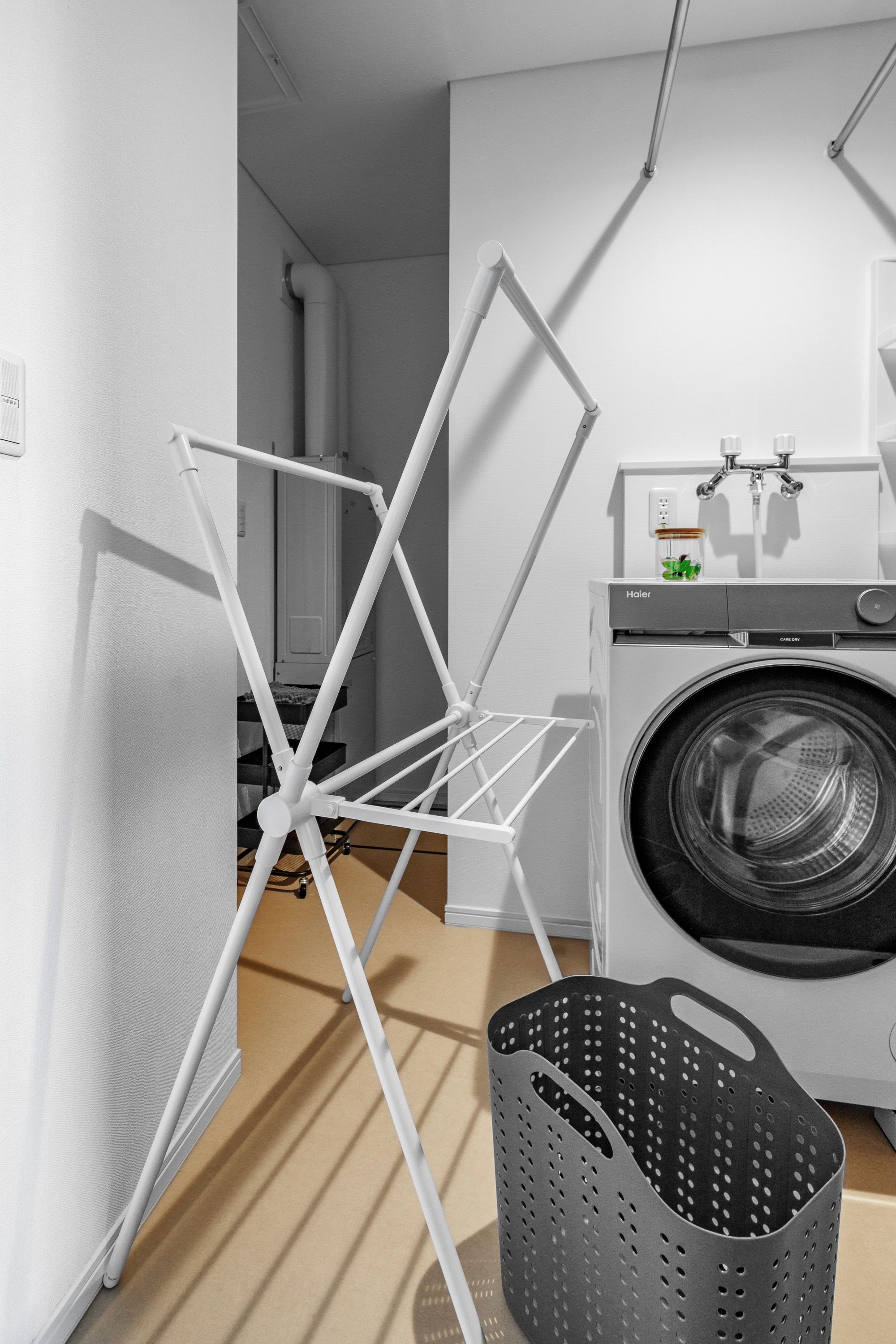 A laundry area with a hanging rack, a washing machine, and a laundry basket.