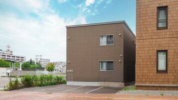 A modern building with a brick facade and a parking lot in front.