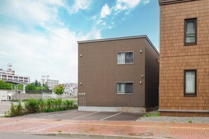 A modern building with a brick facade and a parking lot in front. - Bellezza 101 (Asahikawa)