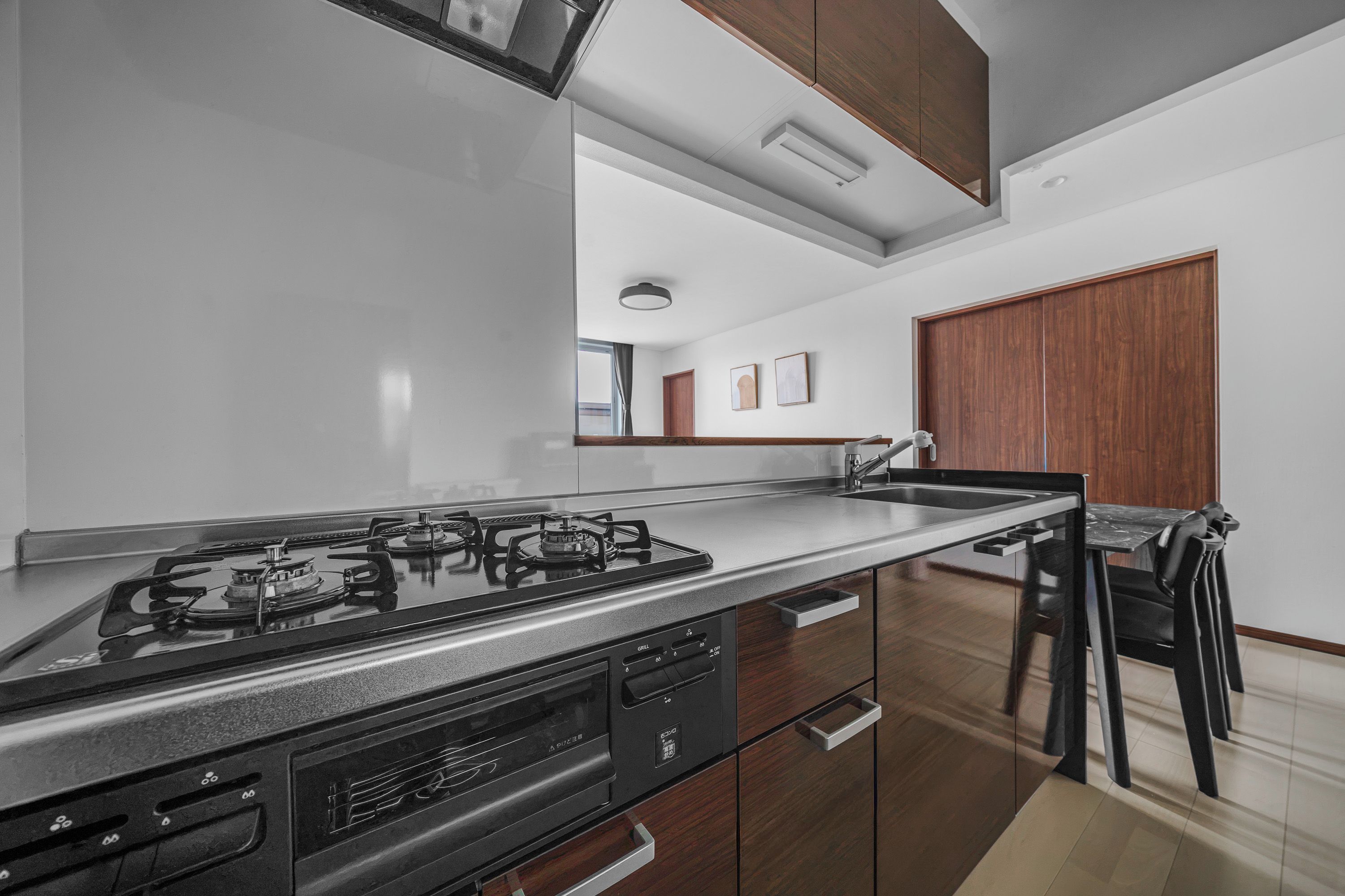 A modern kitchen with a gas stove, wooden cabinets, and a stainless steel countertop.