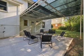 A covered patio with outdoor furniture and a house in the background. - Movie Theatre | SouthPark | Patio | WFH Setup (Charlotte)