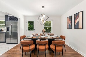 Uma área de refeições moderna com uma mesa retangular, seis cadeiras e um lustre.