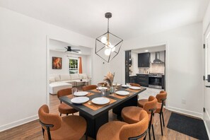 A modern dining area with a rectangular table, six chairs, and a pendant light fixture. - Movie Theatre | SouthPark | Patio | WFH Setup (Charlotte)