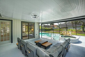 A modern outdoor living area with a pool, a seating area with a table, and a view of the surrounding landscape. - Beautiful Palm Coast Pool House (Palm Coast)