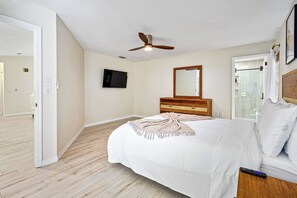 A bedroom with a bed, a ceiling fan, a TV, and a window with curtains. - Beautiful Palm Coast Pool House (Palm Coast)
