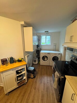 A compact kitchen with a washing machine, a small sink, and a coffee maker. - Entire 1BR + Office, Parking & Garden Access aprmt (Longueuil)