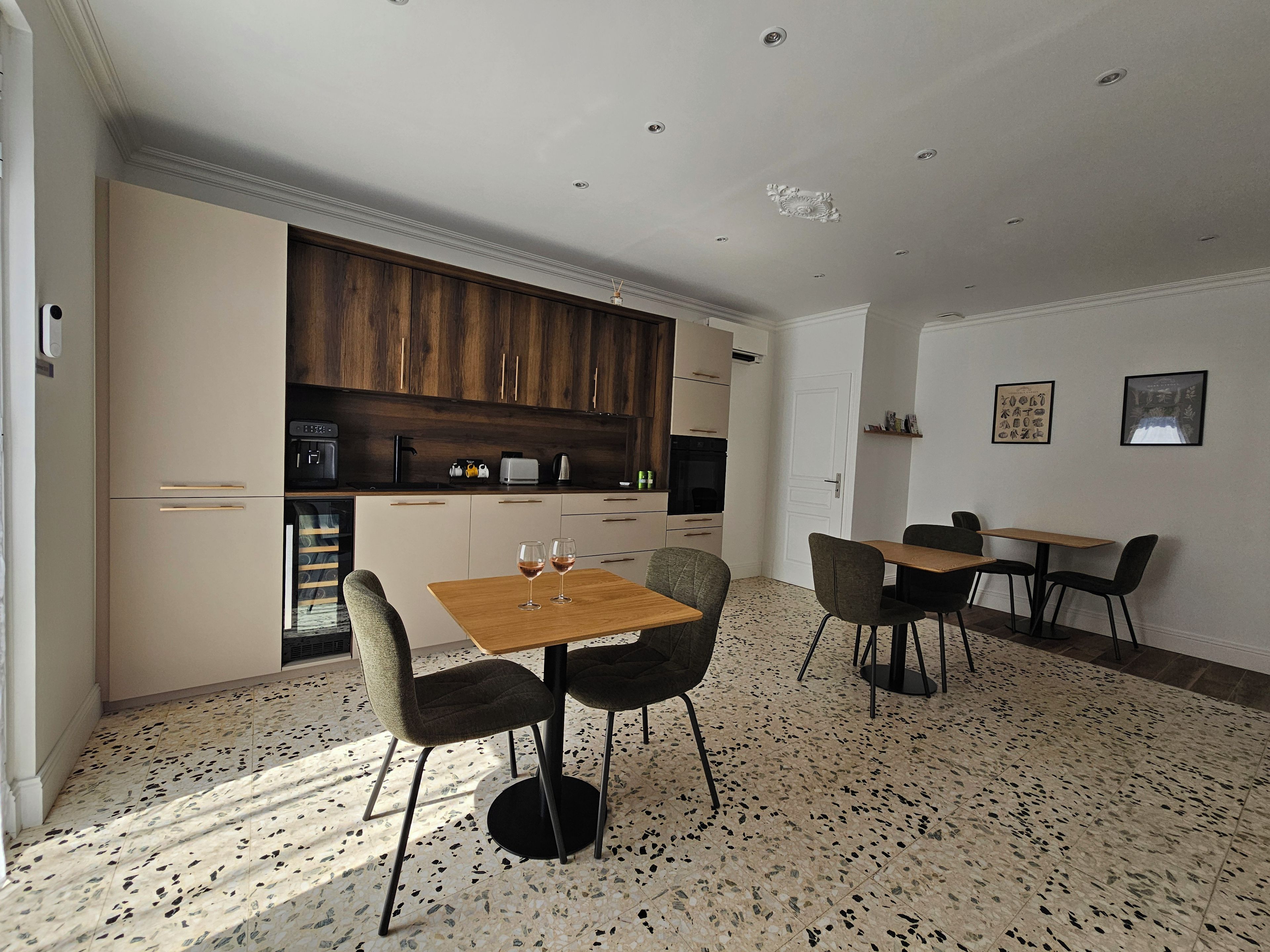 A modern kitchen with wooden cabinets, a dining area with a table and chairs, and a kitchen island.
