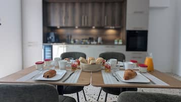 A dining table set for breakfast with croissants, coffee cups, and juice.