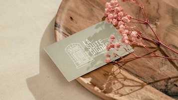 Ett visitkort med en illustration av en byggnad och text, placerat på en träyta med en tygbotten som bakgrund.
