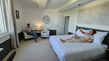 Ett hotellrum med en säng, en sittgrupp med en stol, ett sängbord och en spegel på väggen.