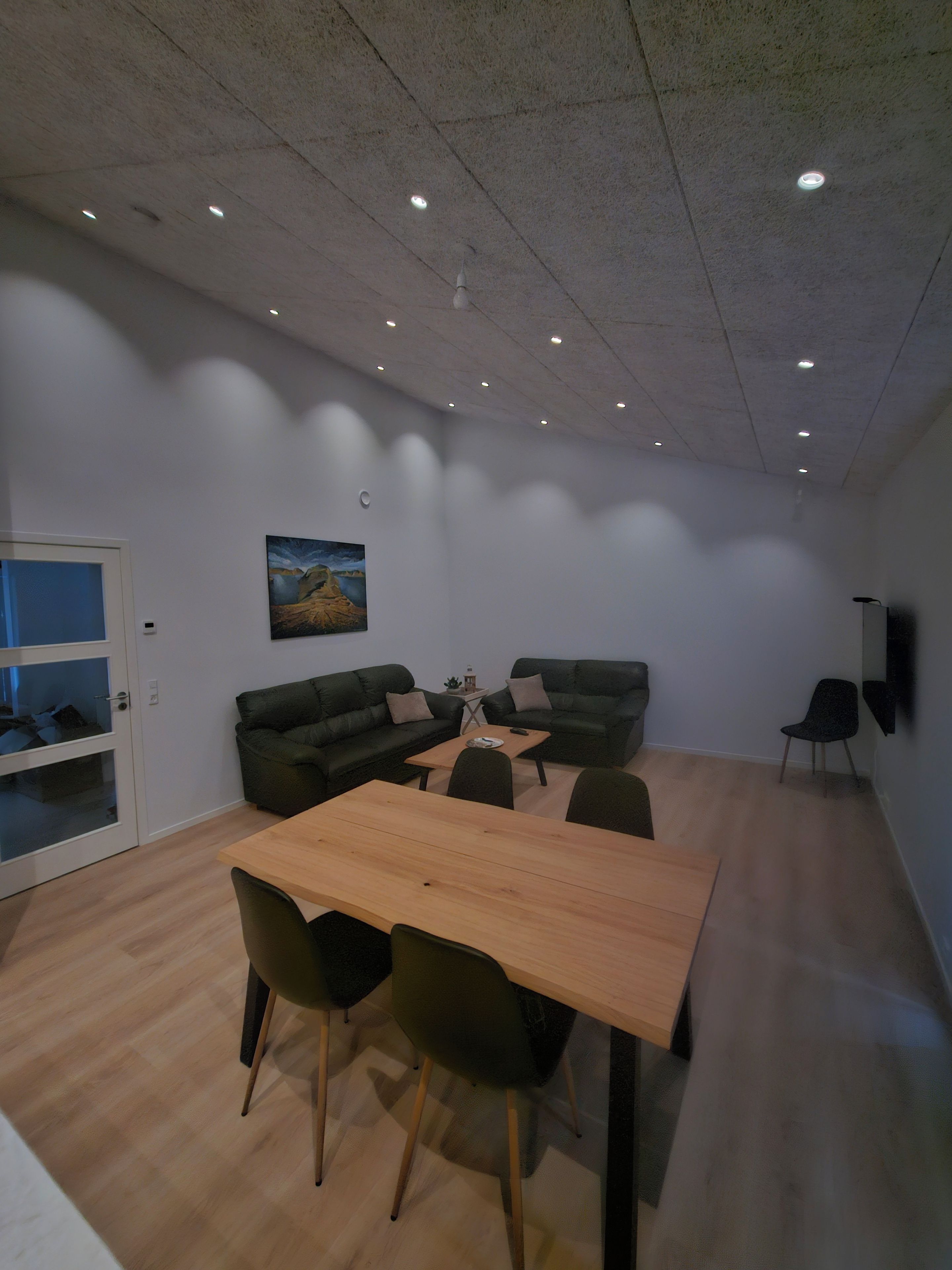 Un salon moderne avec une table à manger en bois, deux canapés et un tableau accroché au mur.