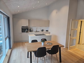 Una cocina moderna con una isla central, una mesa de comedor con sillas y vistas al exterior.