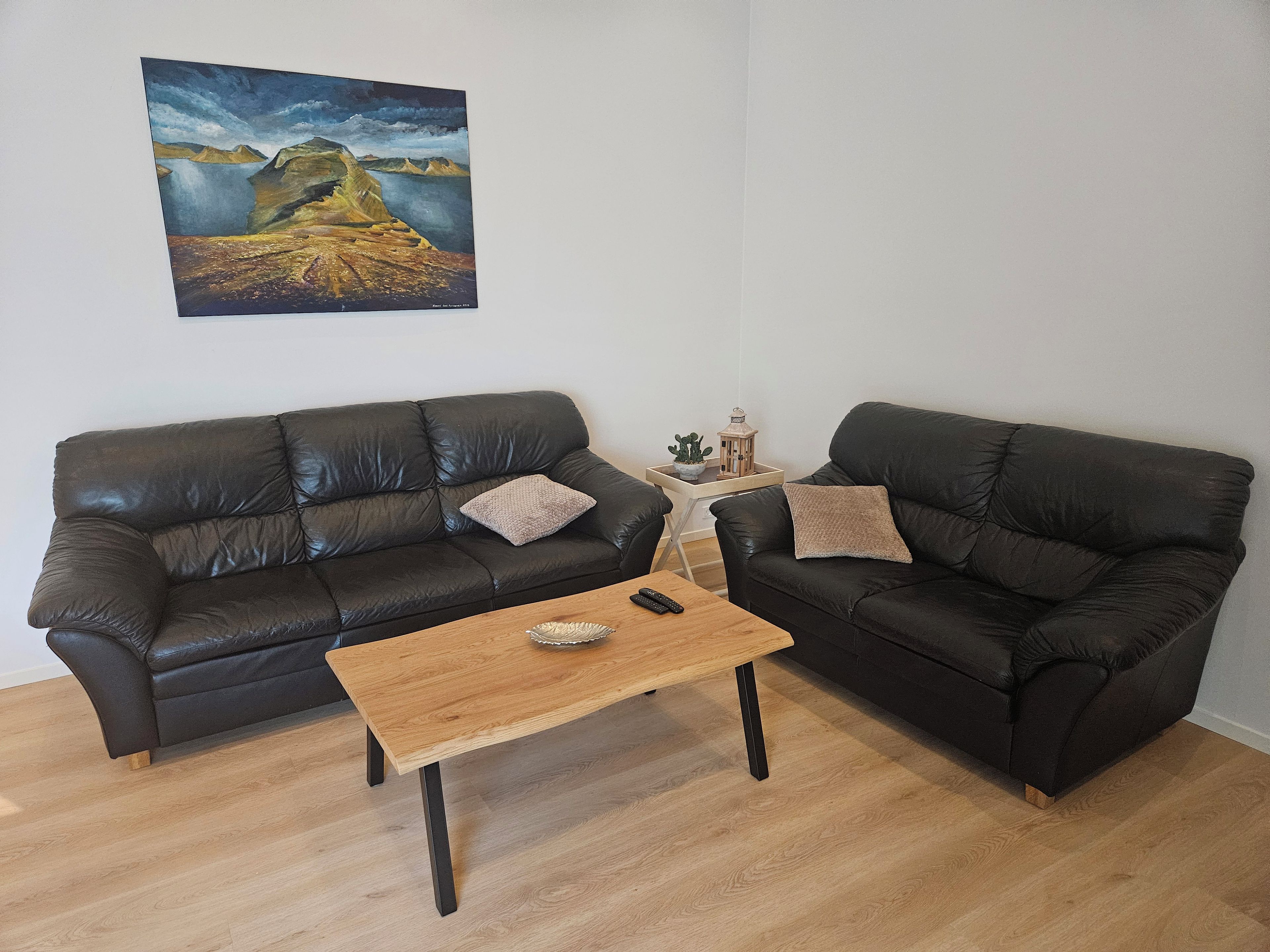 Un soggiorno con due divani in pelle nera, un tavolino in legno e un quadro appeso al muro.