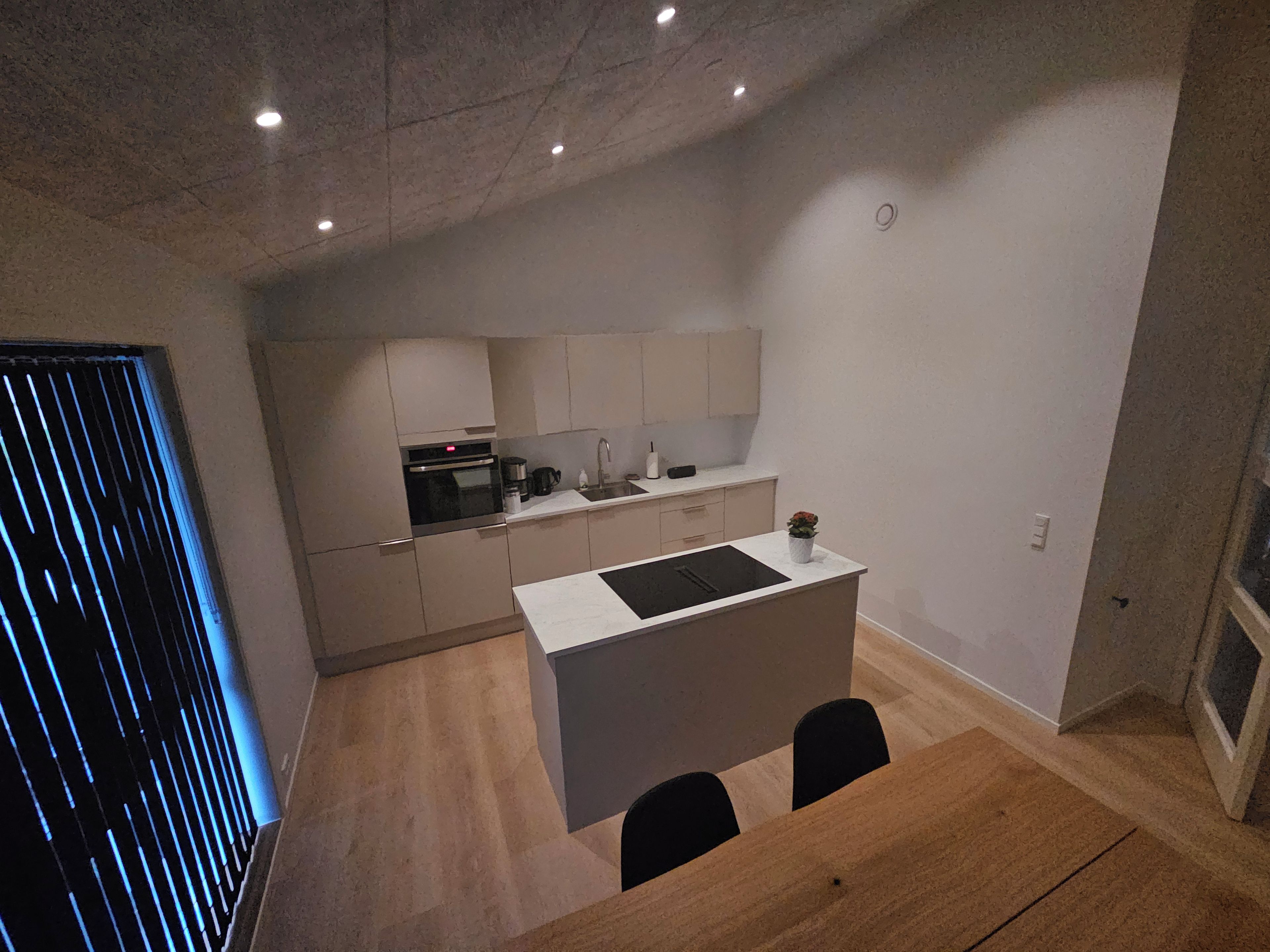 A modern kitchen with a central island, a dining area with a table and chairs, and a view of the adjacent living space.