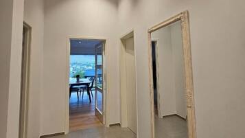 Ein Flur mit einem großen Spiegel an der Wand, der zu einem Zimmer mit Blick führt.