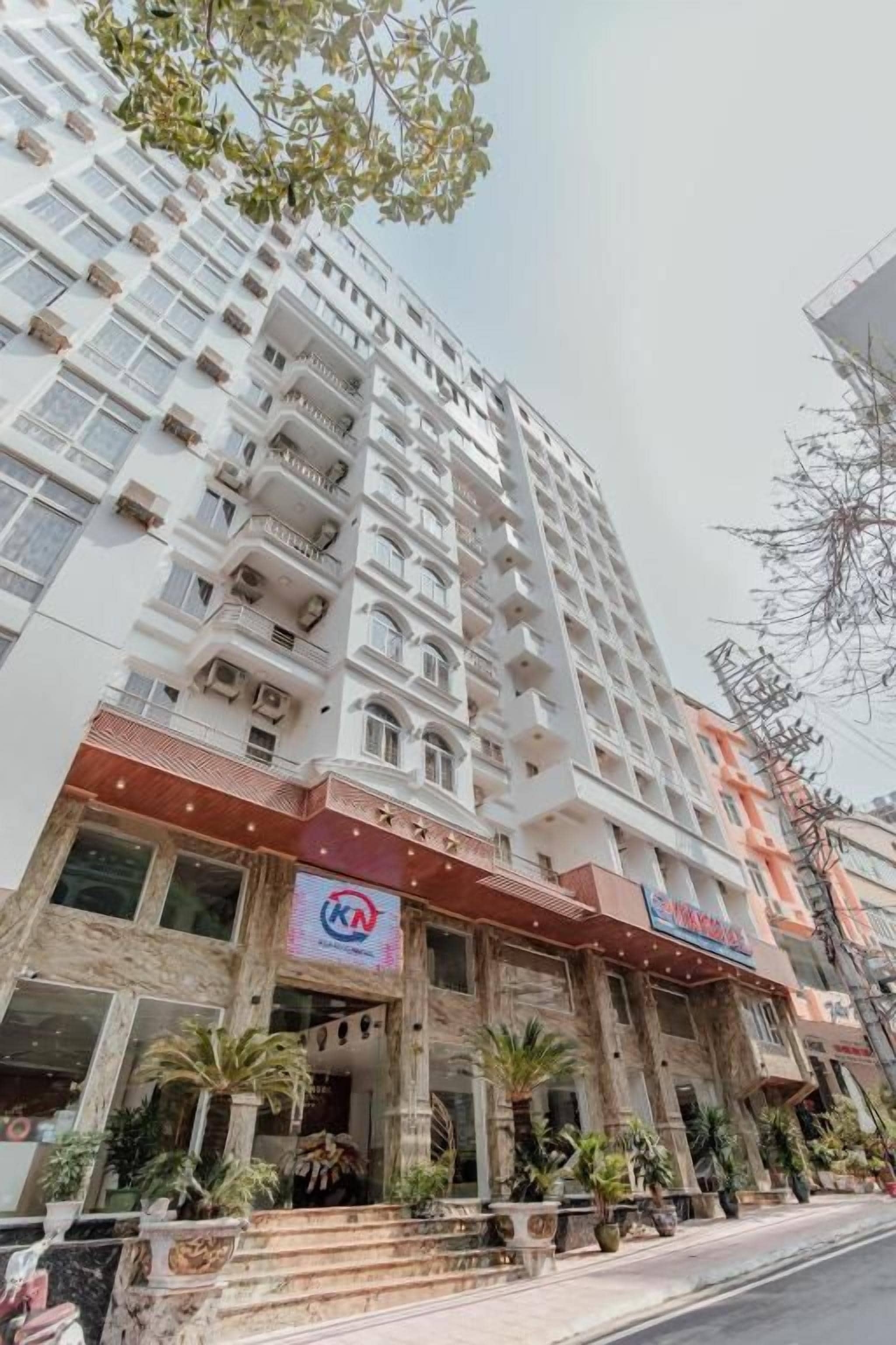 Een hotel met meerdere verdiepingen, een opvallende ingang, balkons en een zichtbaar logo.