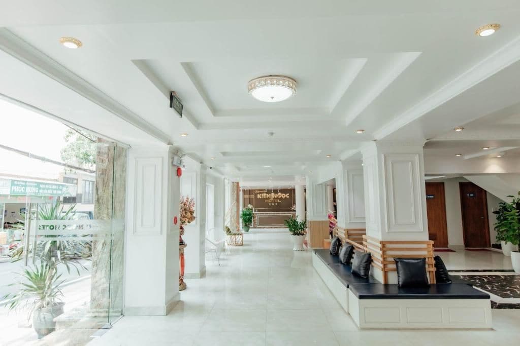 Een hotellobby met een receptiebalie, een zithoek en een trap.