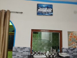 Una habitación con un espejo, un cuadro de caballos y un jarrón de flores en la pared.
