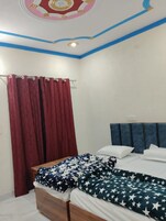 Un dormitorio con cama de madera, cortina roja, cabecero azul y techo con detalles decorativos.